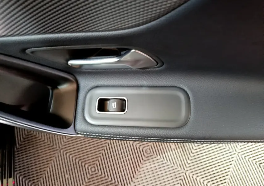 Gros plan sur la poignée de porte intérieure noire et le bouton de verrouillage d’une Mercedes Classe A Berline A 200 d Progressive Line 2022.