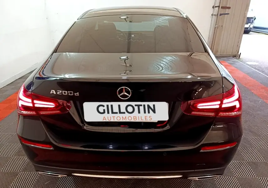 Vue arrière d'une Mercedes Classe A Berline A 200 d noire avec feux LED allumés dans un garage.