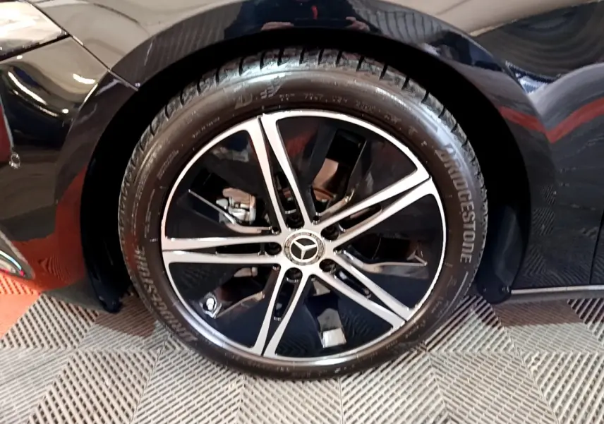 Gros plan sur la roue avant droite noire d’une Mercedes Classe A berline 2022 avec jante alliage bicolore.