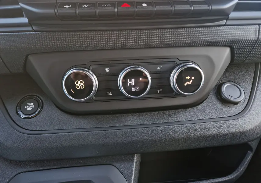 Vue rapprochée du tableau de bord du Renault Trafic Fourgon 2025, montrant les commandes de climatisation et le bouton start/stop.