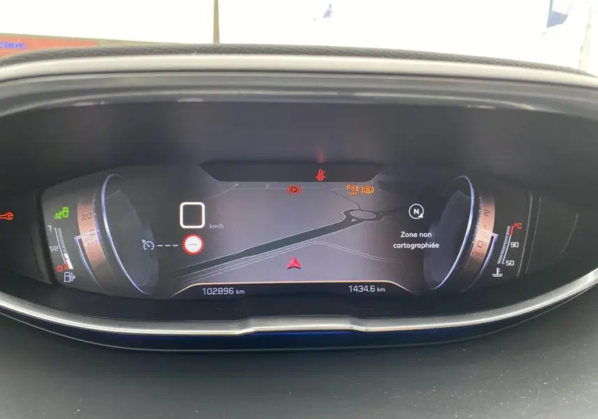 Tableau de bord numérique du Peugeot 3008 blanc, affichant la navigation et les indicateurs de vitesse et température.