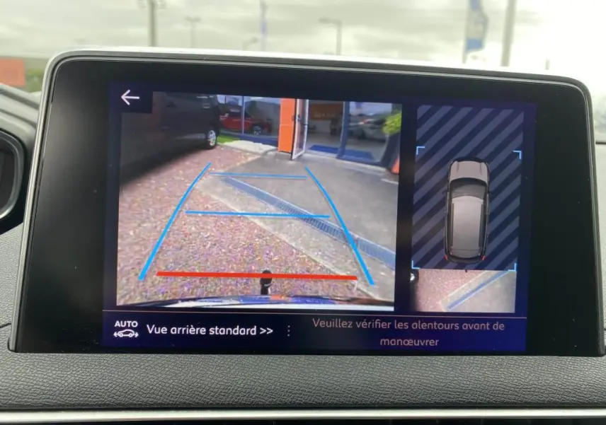 Écran tactile du Peugeot 3008 blanc montrant la caméra de recul avec vue arrière et top-down du véhicule en stationnement.