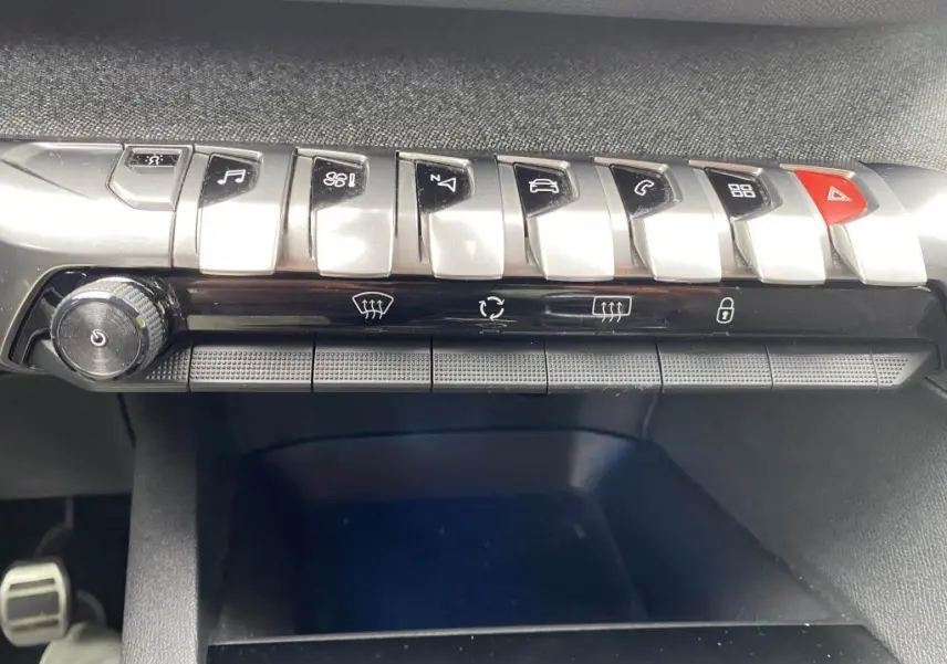 Gros plan sur la rangée de commandes chromées et boutons noirs du tableau de bord du Peugeot 3008 blanc 2018.