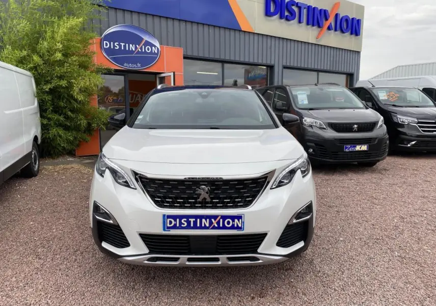 Vue frontale d'un Peugeot 3008 blanc nacré GT Line avec calandre noire et barres de toit en aluminium.