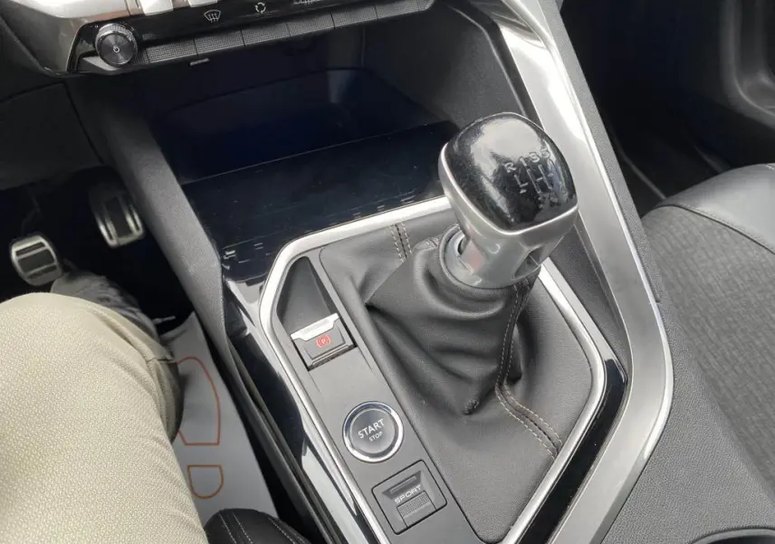 Gros plan sur la console centrale du Peugeot 3008 blanc 2018, mettant en valeur la boîte manuelle et le bouton Start/Stop.