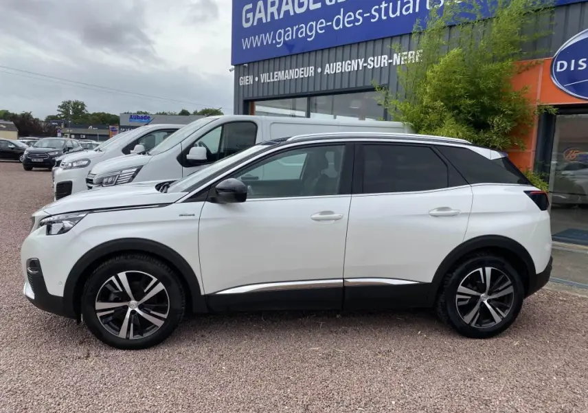 Profil droit d'un Peugeot 3008 blanc nacré GT Line avec barres de toit aluminium et jantes alliage bicolores.