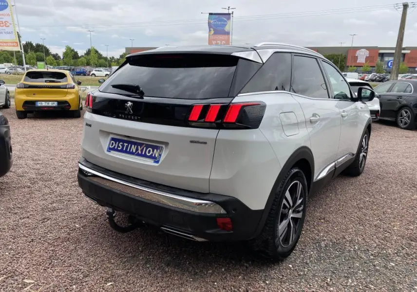 Vue 3/4 arrière droite du Peugeot 3008 blanc nacré avec barres de toit en aluminium et canules d'échappement chromées.