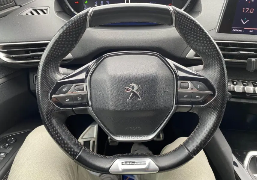 Vue rapprochée du volant compact en cuir perforé avec logo Peugeot et badge GT Line du 3008 blanc de 2018.