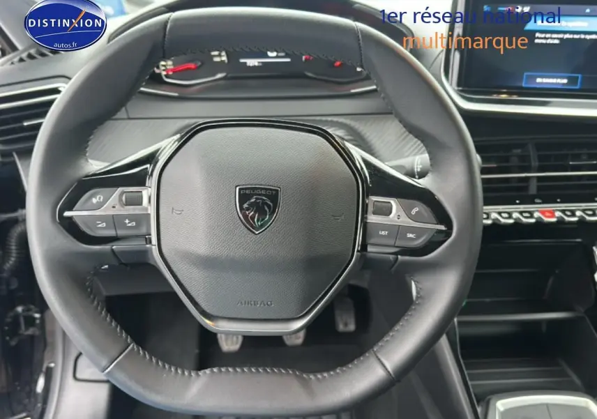 Vue rapprochée du volant cuir noir de la Peugeot 208 1.2 100 style avec commandes intégrées et tableau de bord numérique.
