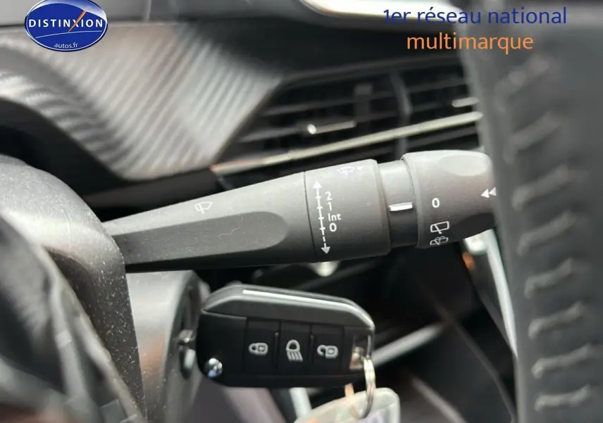 Gros plan sur la manette d’essuie-glace et la clé de contact dans l’habitacle d’une Peugeot 208 noire 2025.
