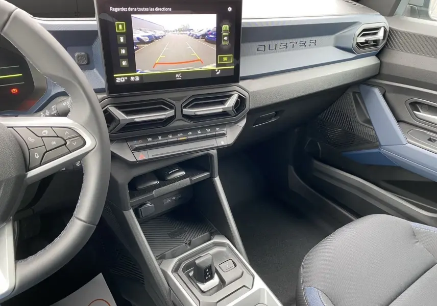 Vue intérieure côté conducteur du Dacia Duster 2025 gris schiste, avec écran tactile central et tableau de bord moderne.