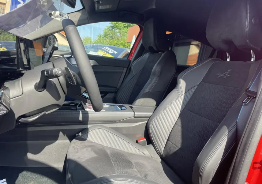 Vue intérieure côté conducteur de la Renault Rafale rouge, sièges sport Alcantara avec surpiqûres et logo Alpine brodé.