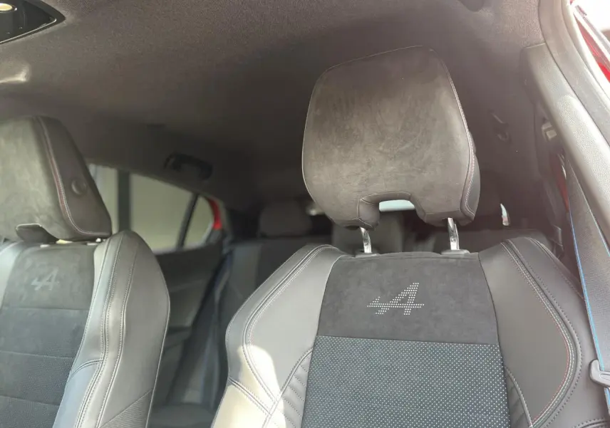 Gros plan sur les sièges avant en Alcantara noir avec surpiqûres tricolores et logo « A » lumineux de la Renault Rafale.