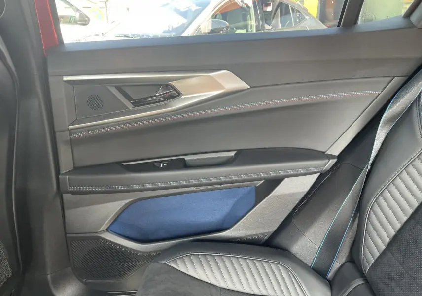 Intérieur côté droit arrière de Renault Rafale rouge, avec porte noire, surpiqûres bleues et siège en cuir noir.