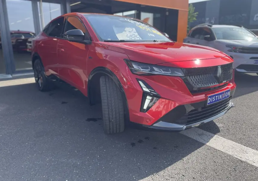 Vue 3/4 avant droit d'une Renault Rafale rouge flamme avec toit noir et calandre noire distinctive.
