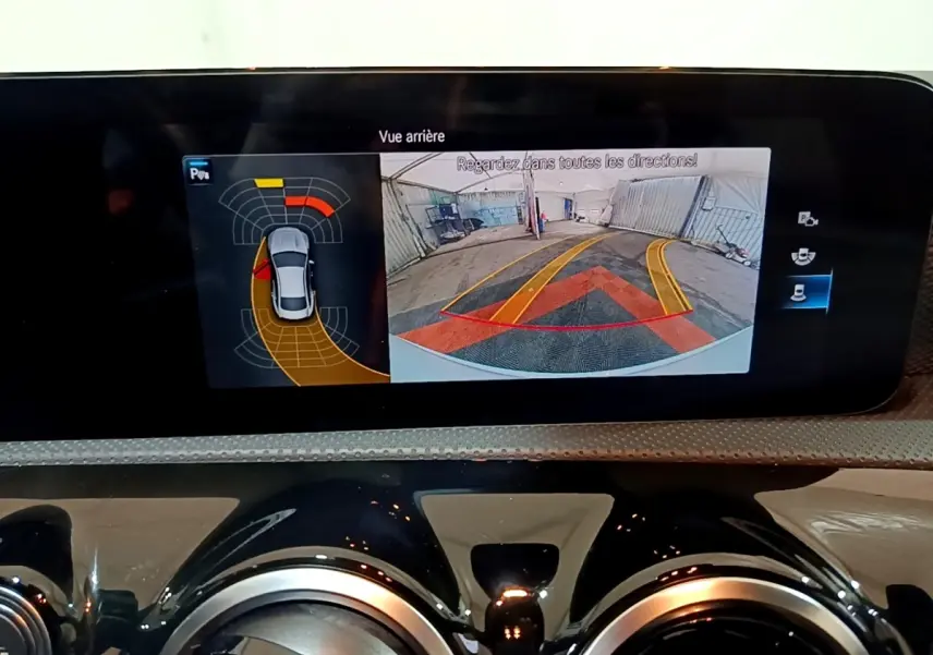 Écran tactile intérieur de la Mercedes CLA 200 d blanc, affichant la caméra de recul avec aides au stationnement.