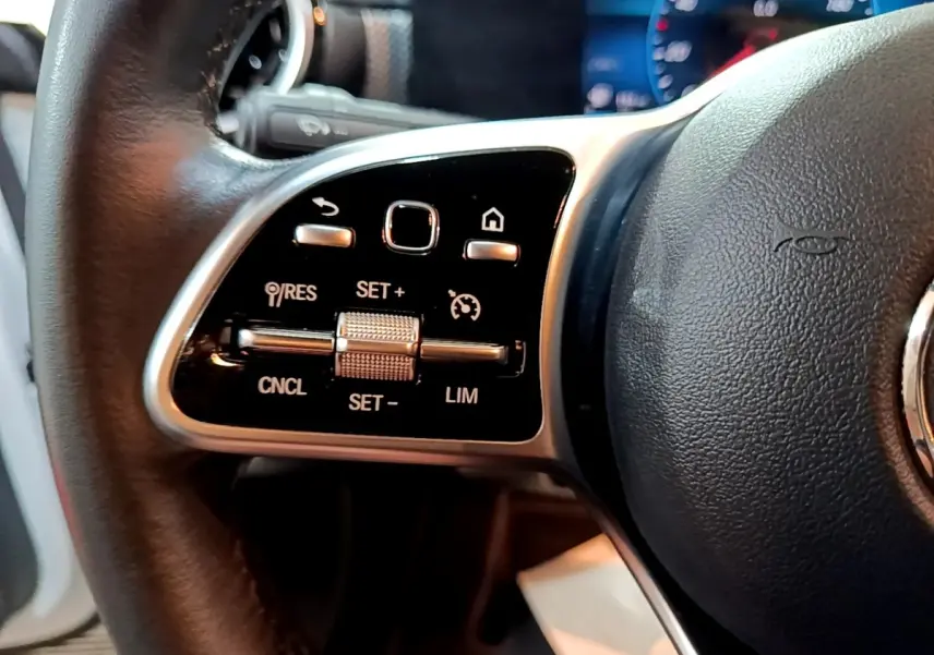 Gros plan sur la partie gauche du volant cuir noir de la Mercedes CLA 200 d Business Line 2021 avec commandes multifonctions.