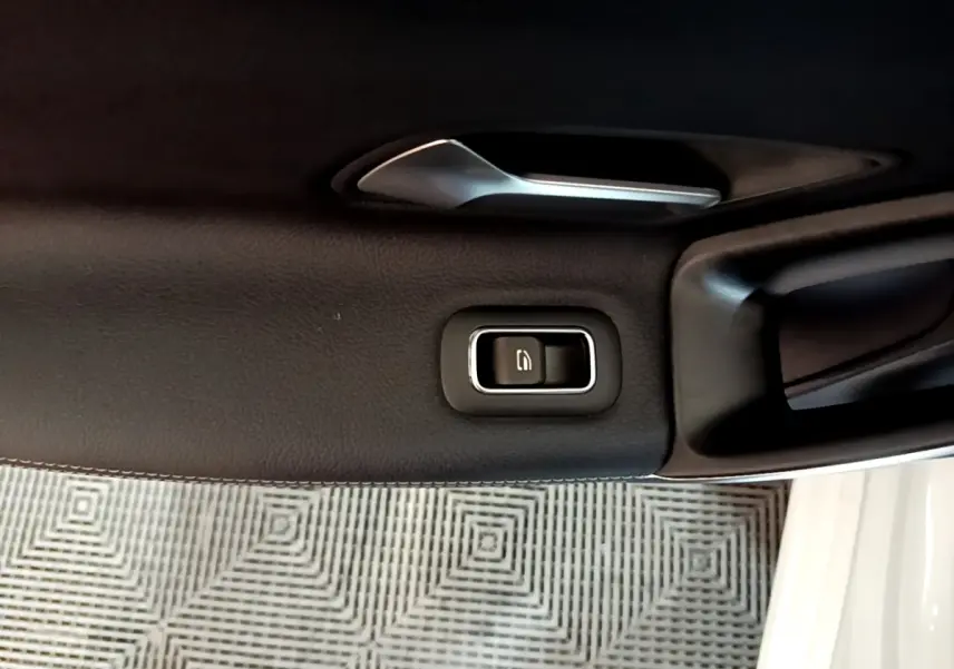 Détail de la poignée intérieure et bouton de verrouillage sur la porte côté gauche d’une Mercedes CLA 200 d Business Line blanche.