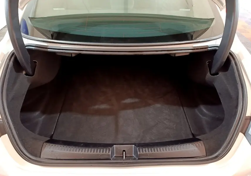 Coffre ouvert vu de dessus d'une Mercedes CLA 200 d Business Line blanche, espace de chargement vide et propre.