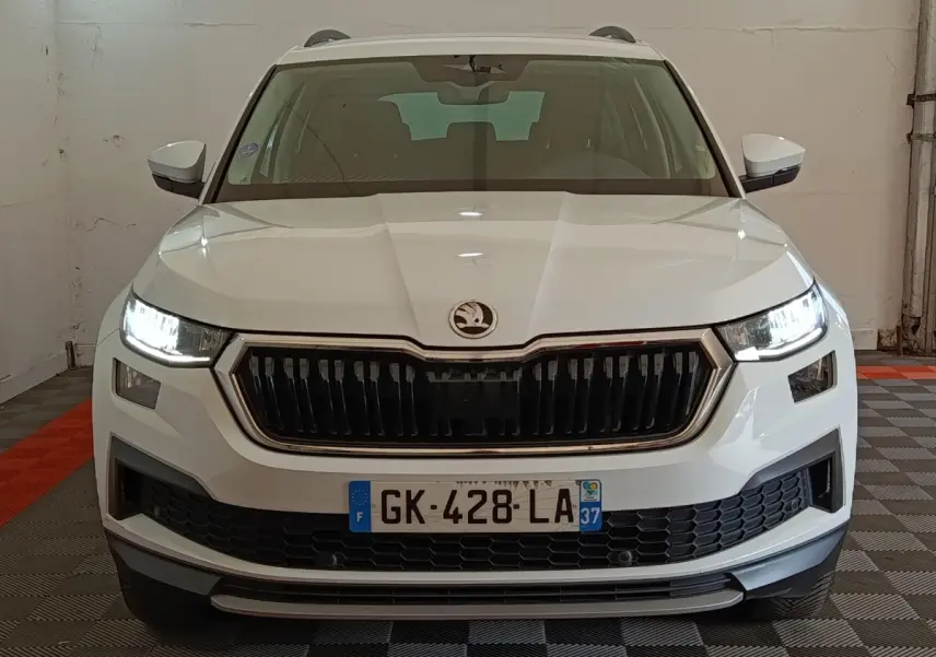 Vue frontale d'un Skoda Kodiaq blanc 2022 avec phares LED allumés et calandre noire distinctive.