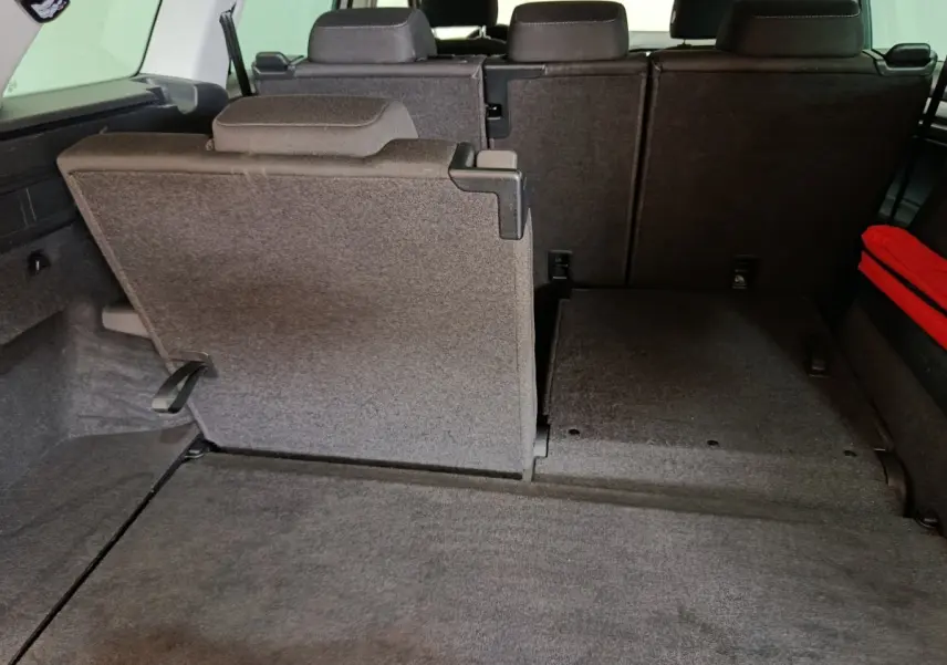 Vue arrière du coffre du Skoda Kodiaq blanc 2022, montrant la troisième rangée de sièges partiellement rabattue en tissu gris.