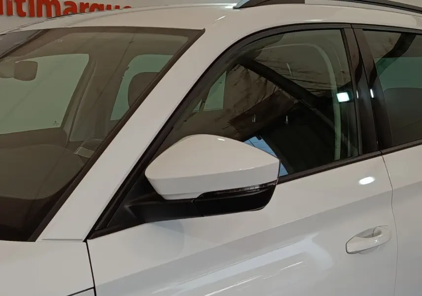 Vue côté gauche avant d'un Skoda Kodiaq blanc, mettant en valeur le rétroviseur et la poignée de porte.