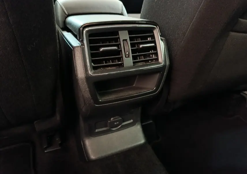 Vue rapprochée des aérateurs arrière noirs et prise 12V au dos des sièges avant dans un Skoda Kodiaq blanc.