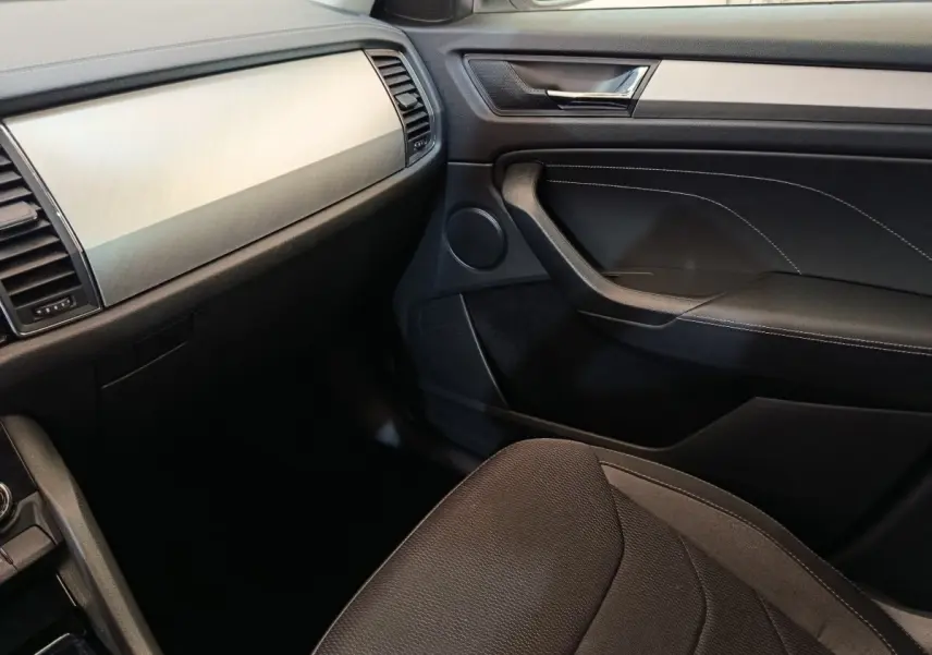 Intérieur côté passager du Skoda Kodiaq 2022, planche de bord claire et garniture noire avec surpiqûres blanches.