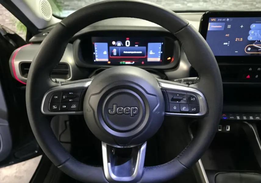 Vue frontale du volant noir Jeep Avenger 2025 avec commandes intégrées et tableau de bord numérique lumineux.