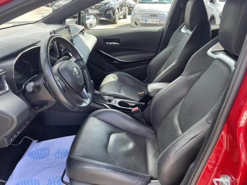 Intérieur de la Toyota Corolla 184 H Collection 2019, vue côté conducteur, sièges cuir noirs et tableau de bord moderne.