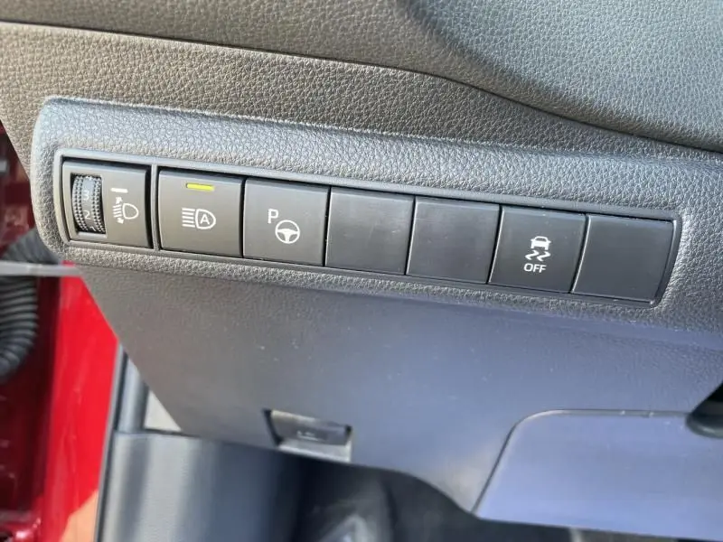 Vue rapprochée des commandes de tableau de bord côté gauche d'une Toyota Corolla 184 H Collection rouge métal avec toit noir.