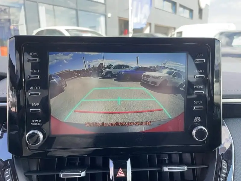 Écran de caméra de recul dans Toyota Corolla 184 H Collection rouge métal, vue arrière avec lignes de guidage vertes et rouges.