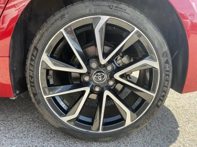 Gros plan sur la roue avant gauche d'une Toyota Corolla 184 H Collection 2019 rouge métal avec jante alliage noire et argentée.