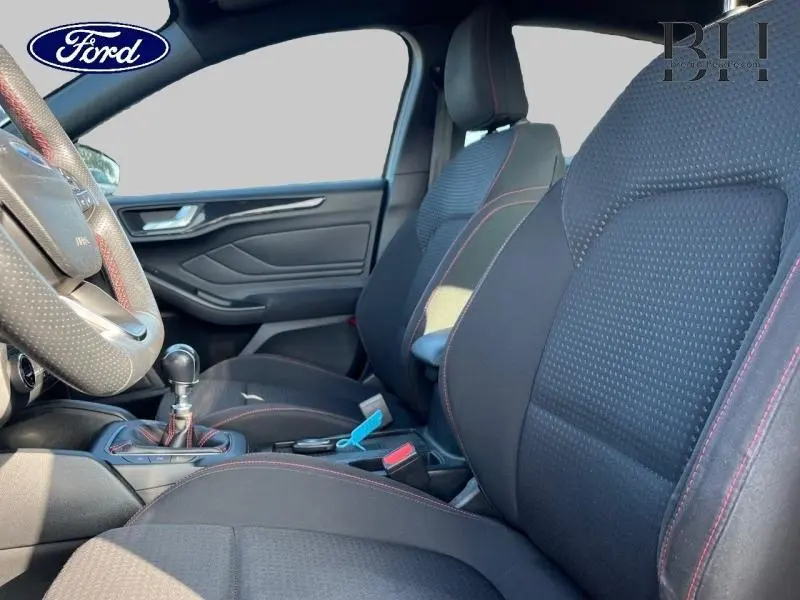 Vue intérieure côté conducteur de la Ford Focus ST Line 2019 avec sièges sport noirs et coutures rouges visibles.