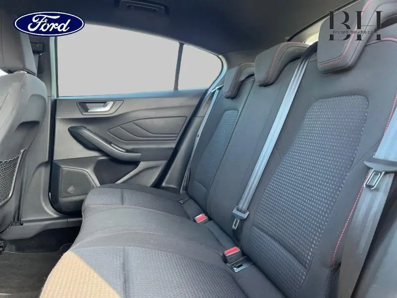 Vue latérale intérieure des sièges arrière noirs avec surpiqûres rouges d'une Ford Focus gris lunaire 2019.