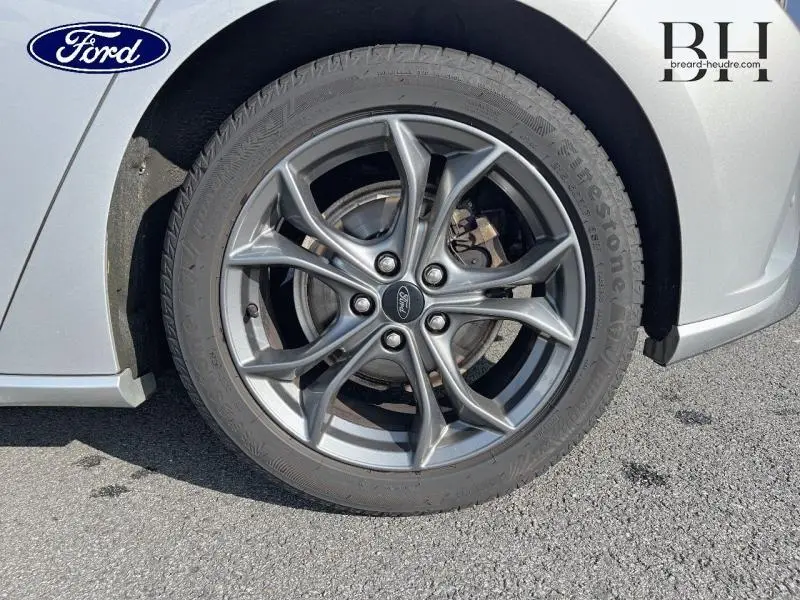 Gros plan sur la jante alu grise et le pneu Firestone d'une Ford Focus gris lunaire, côté avant droit.