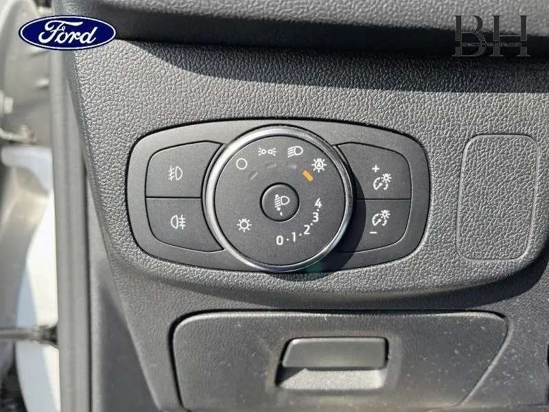 Gros plan sur le bouton de réglage des phares dans l'habitacle de la Ford Focus gris lunaire 2019 côté conducteur.