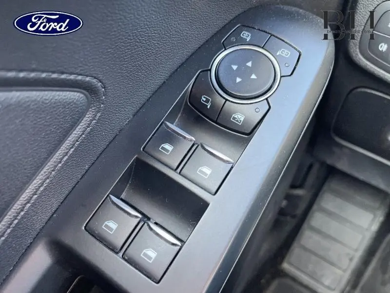 Gros plan sur les commandes des vitres électriques et rétroviseurs côté conducteur d'une Ford Focus gris lunaire 2019.