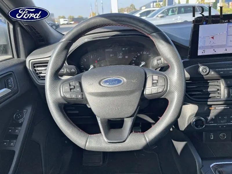 Vue rapprochée du volant cuir multifonction de la Ford Focus gris lunaire, avec écran tactile et commandes au volant visibles.