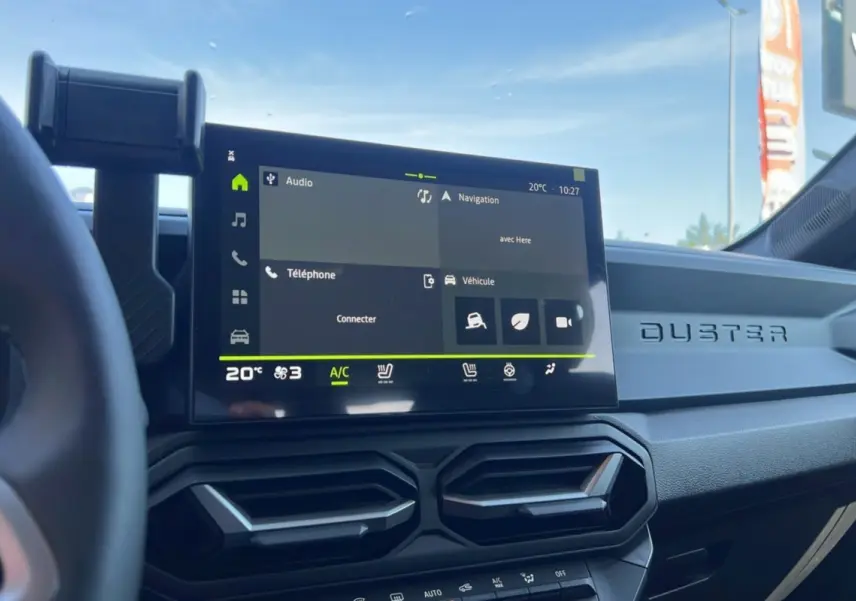 Tableau de bord du Dacia Duster 2025 blanc glacier, vue intérieure centrée sur l'écran tactile et les aérateurs hexagonaux.