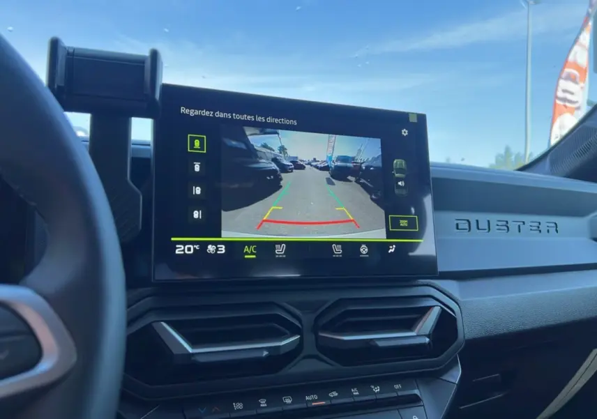 Vue intérieure du tableau de bord du Dacia Duster 2025 avec écran de caméra de recul et logo Duster en relief.