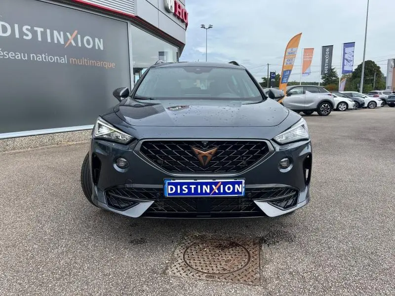 Vue de face du CUPRA Formentor gris magnétique métallisé avec calandre noire et logo cuivre, stationné devant un concessionnaire.