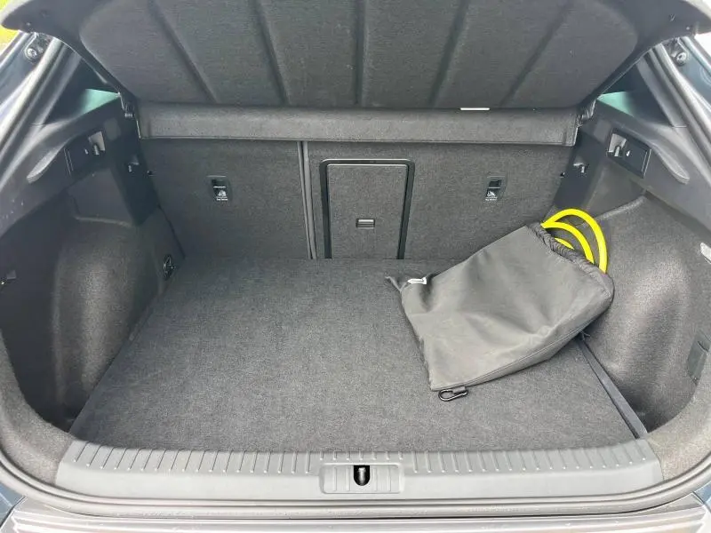 Coffre ouvert du CUPRA Formentor gris métallique 2024, montrant un sac noir avec câble de recharge jaune.