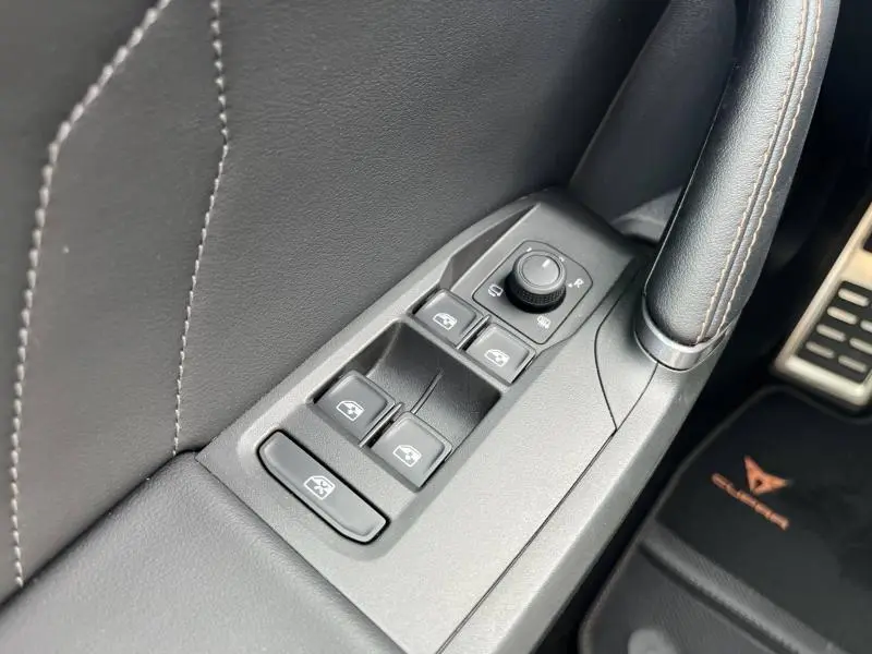 Gros plan sur les commandes de lève-vitres et rétroviseurs côté conducteur du CUPRA Formentor 1.4 e-HYBRID 2024 en intérieur noir.