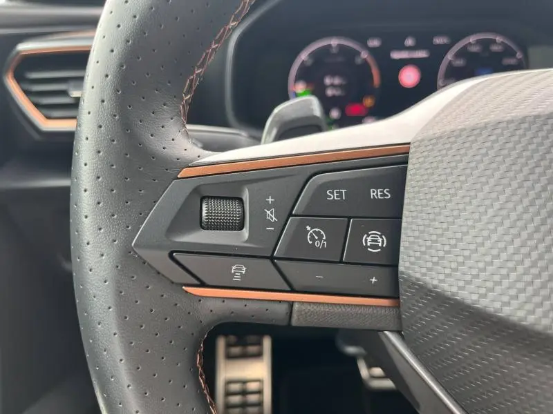 Gros plan sur les commandes à gauche du volant sport perforé avec surpiqûres cuivre du CUPRA Formentor gris Magnétique 2024.