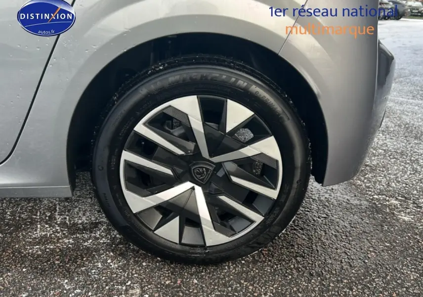 Gros plan sur la roue arrière droite d'une Peugeot 208 gris artense avec jante alliage au design géométrique.