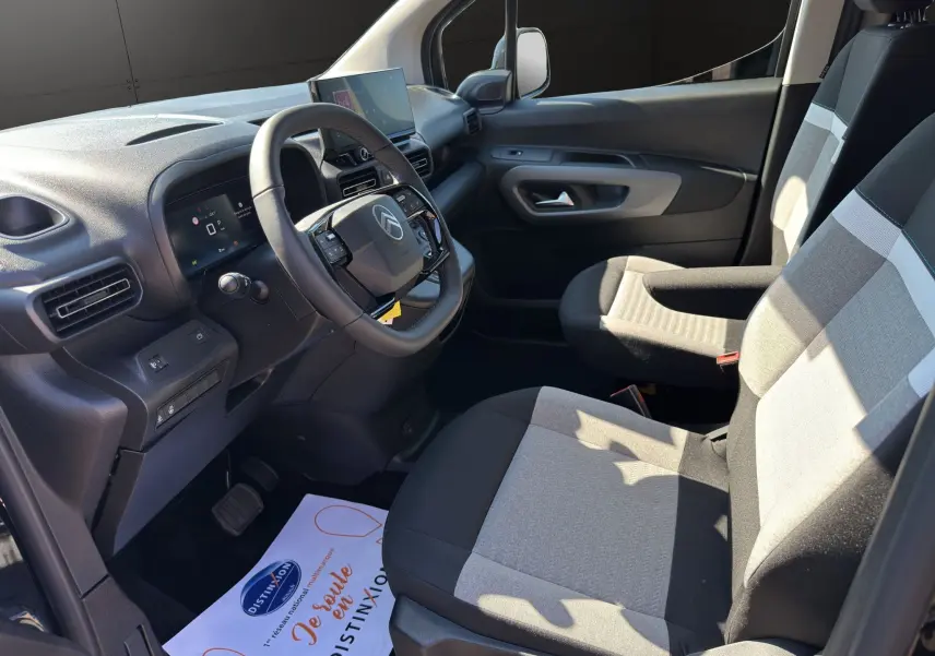 Vue intérieure côté conducteur du Citroën Berlingo 2025 noir, avec tableau de bord moderne et sièges tissu bicolore gris.