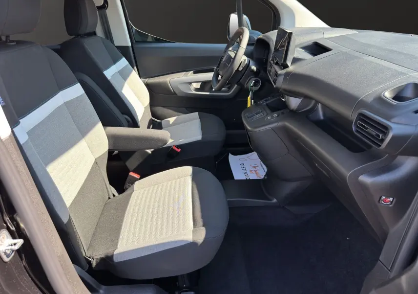 Vue intérieure côté gauche du Citroën Berlingo noir 2025, montrant les sièges avant en tissu bicolore et le tableau de bord moderne.