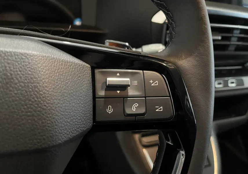 Gros plan sur les commandes au volant cuir noir du Peugeot Expert Fourgon blanc, avec tableau de bord en arrière-plan.