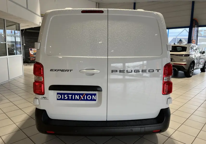 Vue arrière d’un Peugeot Expert Fourgon blanc avec portes battantes et pare-chocs noir en showroom.